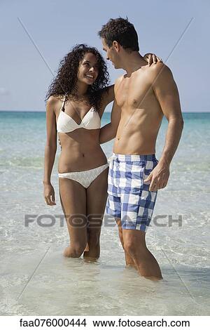 Picture - Couple wading in water at the beach. Fotosearch