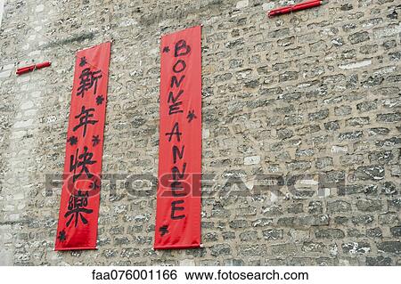 Stock Photograph - Couplets in with Chinese and Western scripts hanging on brick wall. Fotosearch