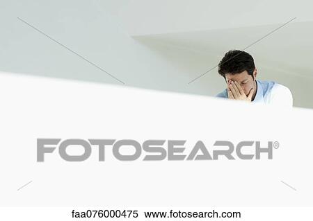 Stock Photography - Distressed man covering face with hands. Fotosearch