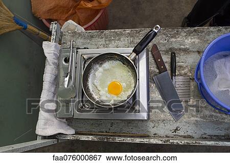 Stock Photo - Egg frying in pan on hot plate, overhead view. Fotosearch