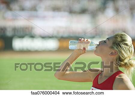 Female athlete drinking bottled water View Large Photo Image Picture - Female athlete drinking bottled water. Fotosearch