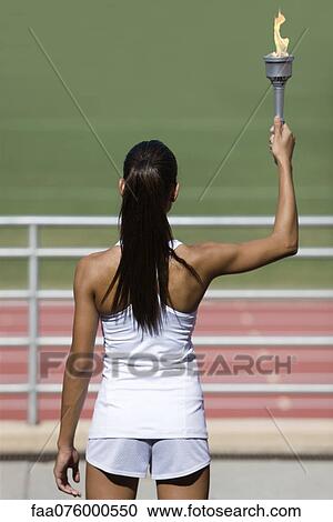 Female athlete holding up torch, rear view View Large Photo Image Stock Image - Female athlete holding up torch, rear view. Fotosearch