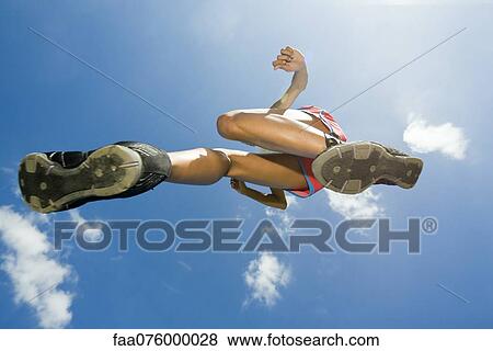 Stock Photo - Female athlete jumping in air, directly below. Fotosearch