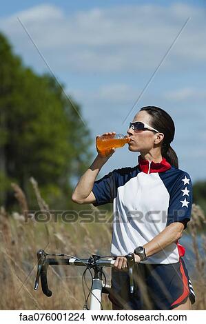Picture - Female cyclist drinking sports drink. Fotosearch