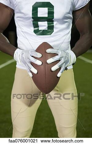 Stock Image - Football player holding football, cropped. Fotosearch