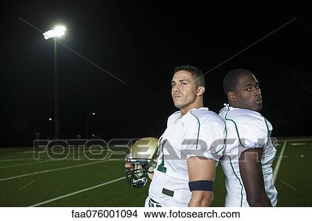 Picture - Football players standing back to back on field. Fotosearch
