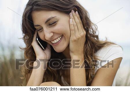 Stock Image - Happy young woman talking on cell phone, portrait. Fotosearch