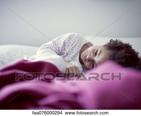 Little girl lying on bed, looking away in thought View Large Photo Image Picture - Little girl lying on bed, looking away in thought. Fotosearch