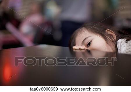 Stock Photo - Little girl peeking over edge of table. Fotosearch