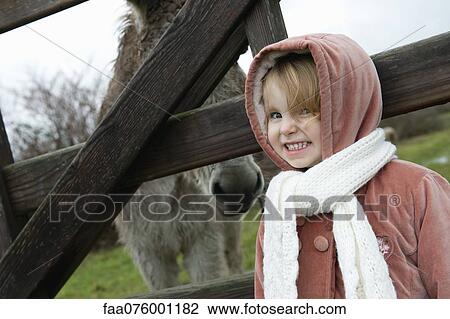 Little girl posing for picture with donkey behind fence, portrait View Large Photo Image Stock Image - Little girl posing for picture with donkey behind fence, portrait. Fotosearch