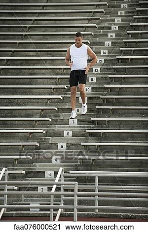 Stock Image - Male athlete running down stadium steps. Fotosearch