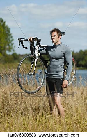 Man carrying bicycle on shoulder in nature, portrait View Large Photo Image Stock Image - Man carrying bicycle on shoulder in nature, portrait. Fotosearch