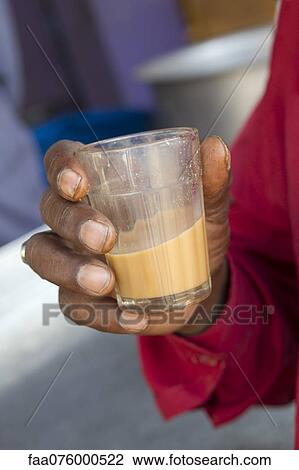 Stock Image - Man holding glass of chai tea, cropped. Fotosearch