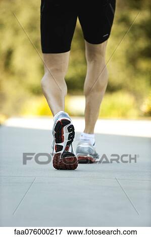 Stock Photo - Man in sport shoes walking, low section, rear view. Fotosearch