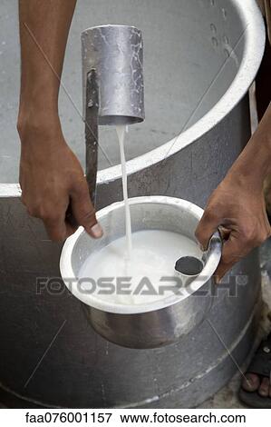 Stock Photo - Man ladling fresh milk into pot, cropped. Fotosearch