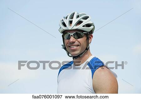 Stock Photo - Man wearing cycling helmet and sunglasses, portrait. Fotosearch