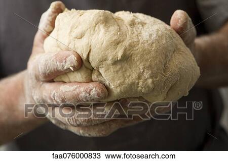 Stock Image - Man's hands holding fresh bread dough. Fotosearch