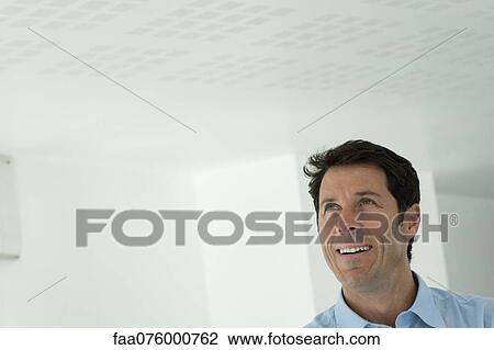 Stock Image - Mature man looking up and smiling, portrait. Fotosearch