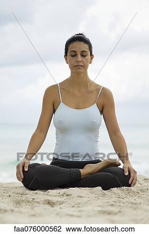 Stock Image - Mature woman meditating on beach, portrait. Fotosearch
