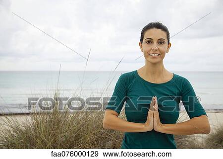 Stock Photo - Mature woman practicing yoga on beach, portrait. Fotosearch