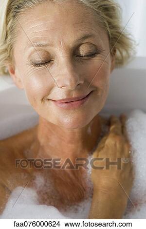 Mature woman relaxing in bubble bath with eyes closed, portrait View Large Photo Image Picture - Mature woman relaxing in bubble bath with eyes closed, portrait. Fotosearch