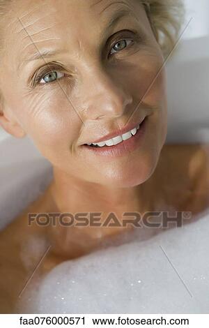 Stock Image - Mature woman relaxing in bubble bath, cropped. Fotosearch
