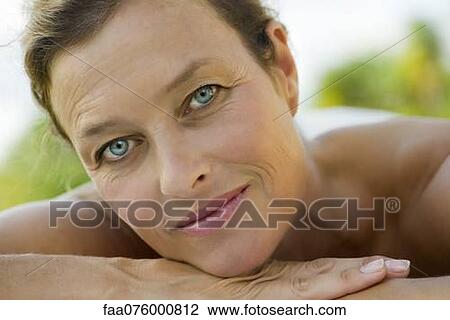 Stock Image - Mature woman resting head on arms, portrait. Fotosearch