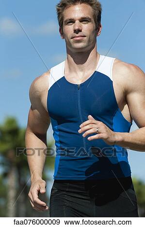 Stock Photo - Mid-adult man in sports clothing running, portrait. Fotosearch