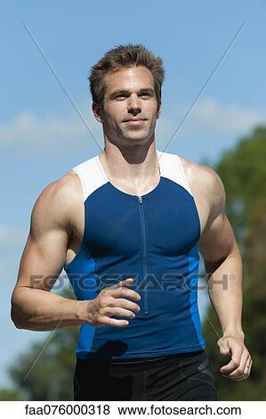 Stock Photo - Mid-adult man in sports clothing running, portrait. Fotosearch
