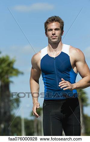 Stock Photo - Mid-adult man in sports clothing running, portrait. Fotosearch