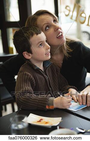 Stock Photograph - Mother and son checking results for lottery ticket. Fotosearch