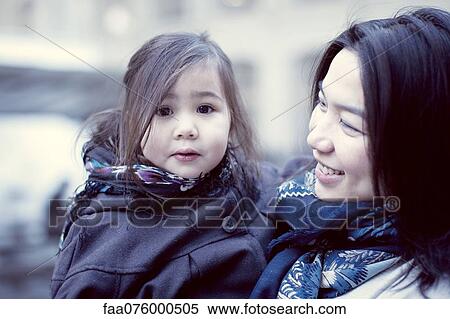 Stock Photography - Mother and young daughter outdoors, girl looking at camera. Fotosearch