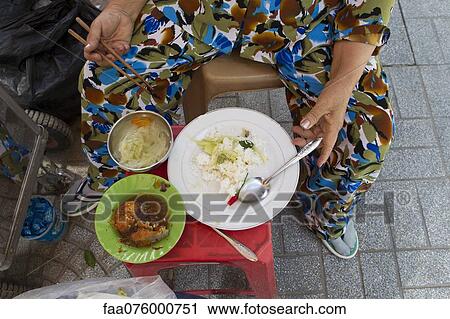 Stock Image - Person eating street food, cropped. Fotosearch