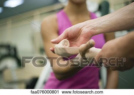 Stock Image - Person wrapping bandage around woman's hand, cropped. Fotosearch