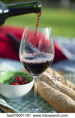 Stock Image - Pouring red wine at picnic. Fotosearch
