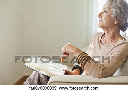 Senior woman reading book on sofa View Large Photo Image Stock Photo - Senior woman reading book on sofa. Fotosearch
