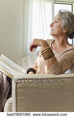 Senior woman reading book on sofa View Large Photo Image Stock Photography - Senior woman reading book on sofa. Fotosearch