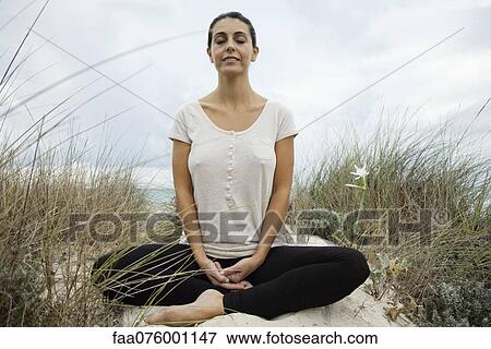 Stock Photo - Smiling mature woman meditating on beach, portrait. Fotosearch
