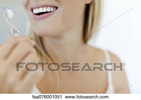 Stock Image - Smiling woman brushing teeth, cropped. Fotosearch