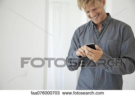 Smiling young man using smartphone View Large Photo Image Stock Image - Smiling young man using smartphone. Fotosearch