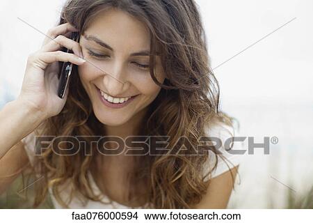Picture - Smiling young woman talking on cell phone. Fotosearch