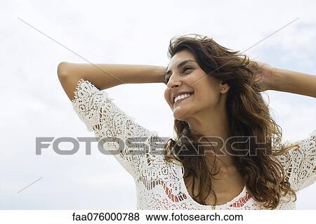 Smiling young woman with hands on head, low angle view View Large Photo Image Stock Photo - Smiling young woman with hands on head, low angle view. Fotosearch