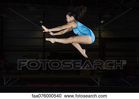 Teenage girl gymnast jumping on balance beam View Large Photo Image Stock Image - Teenage girl gymnast jumping on balance beam. Fotosearch