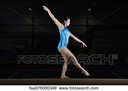 Stock Photo - Teenage girl gymnast performing on balance beam. Fotosearch