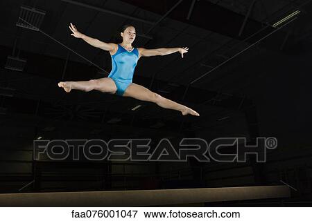 Stock Photo - Teenage girl gymnast performing split leap. Fotosearch