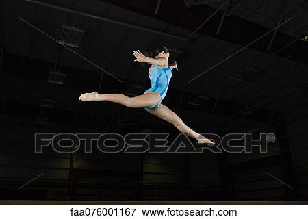 Teenage girl gymnast performing split leap, low angle view View Large Photo Image Stock Photo - Teenage girl gymnast performing split leap, low angle view. Fotosearch