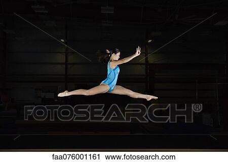 Stock Image - Tenage girl gymnast performing split leap. Fotosearch