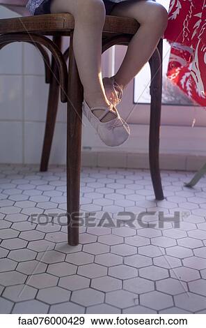 Stock Photo - Toddler girl sitting in chair, low section. Fotosearch