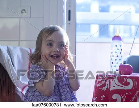 Stock Image - Toddler girl touching face in surprise, portrait. Fotosearch