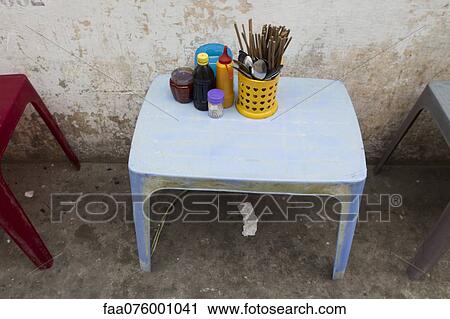 Stock Image - Utensils and condiments on table in sidewalk cafe. Fotosearch
